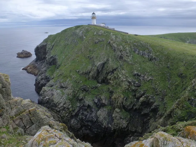 The Flannan Isles Lighthouse on Eilean Mor, with surrounding cliffs and the open Atlantic beyond.